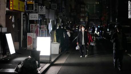 People walk down a street during a power outage in Tokyo.