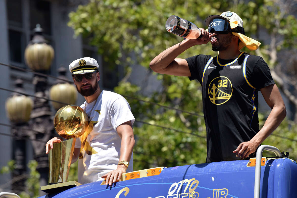 Otto Porter Jr., right, drinks a drink of Moët champagne as he proceeds down Market Street with Klay Thompson, during the Warriors victory parade, Monday, June 20, 2022. 