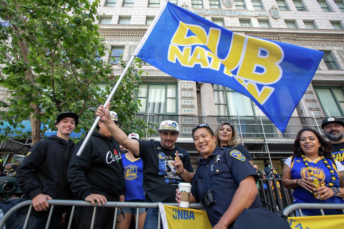 A fan holds the Dub Nation flag during a review of the Golden State Warriors Championship on Market Street in San Francisco, California on June 20, 2022.