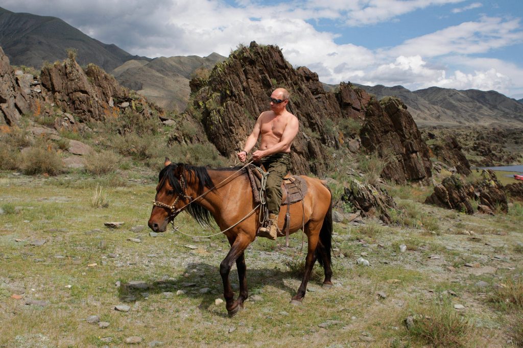 Russian President Vladimir Putin rides a horse without a shirt.