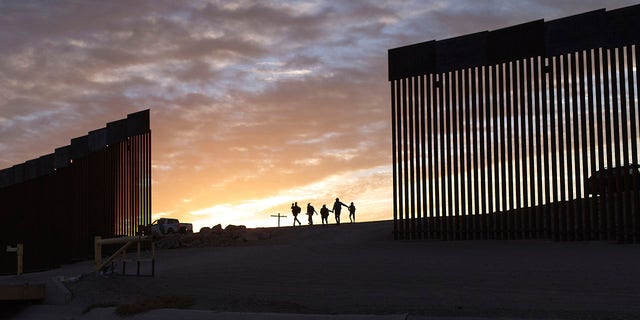 FILE - Immigrant families from Brazil pass through a gap in the border wall to reach the United States after crossing from Mexico to Yuma, Arizona, to seek asylum.