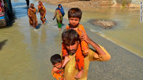 A displaced man carries his daughters from his flood-damaged home in Jafarabad, a district in Pakistan's southwestern Balochistan province, on Saturday. 
