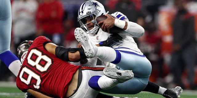 Anthony Nelson, No. 98 of the Tampa Bay Buccaneers, Dak Prescott, No. 4 of the Dallas Cowboys, is reported during the second half at AT&T Stadium  T on September 11, 2022 in Arlington, Texas.