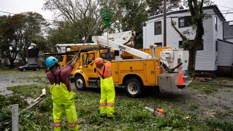 Workers lift a cut wire to allow machines to reach deciduous trees in Halifax, Nova Scotia, on Saturday.
