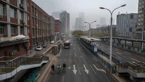 People ride bicycles on an empty street near the central business district in Beijing on November 24. 
