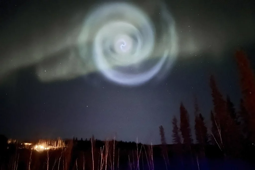 A strange spiral appears amidst the northern lights in the Alaskan night sky