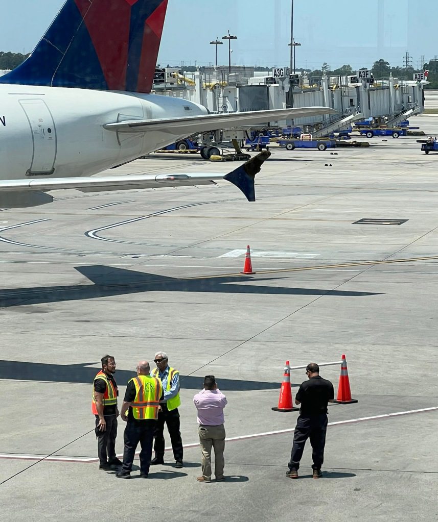 Airport workers near a Delta plane