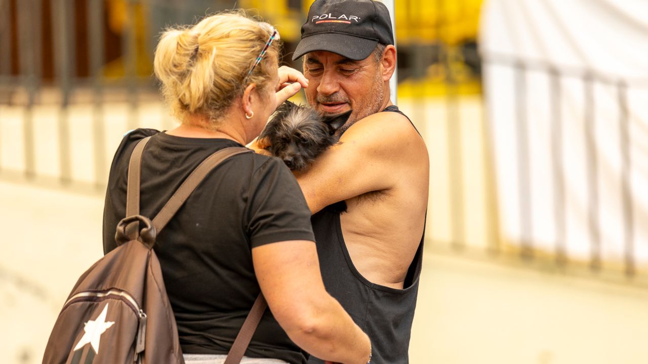 Two evacuees due to the fire hug their dog on Saturday in La Orotava.