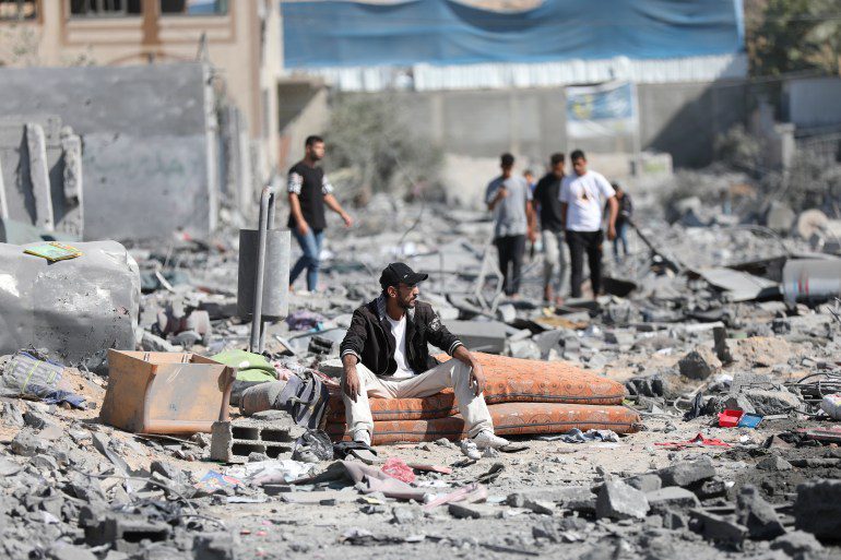 Palestinians walk next to buildings destroyed by Israeli bombing on the Al-Zahraa neighborhood on the outskirts of Gaza City.