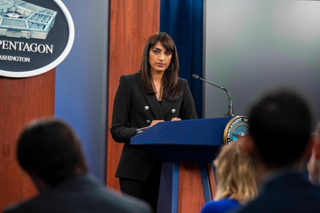 Deputy Pentagon Press Secretary Sabrina Singh stands at a lectern with the Pentagon seal in the background and blurred reporters seated in the foreground.