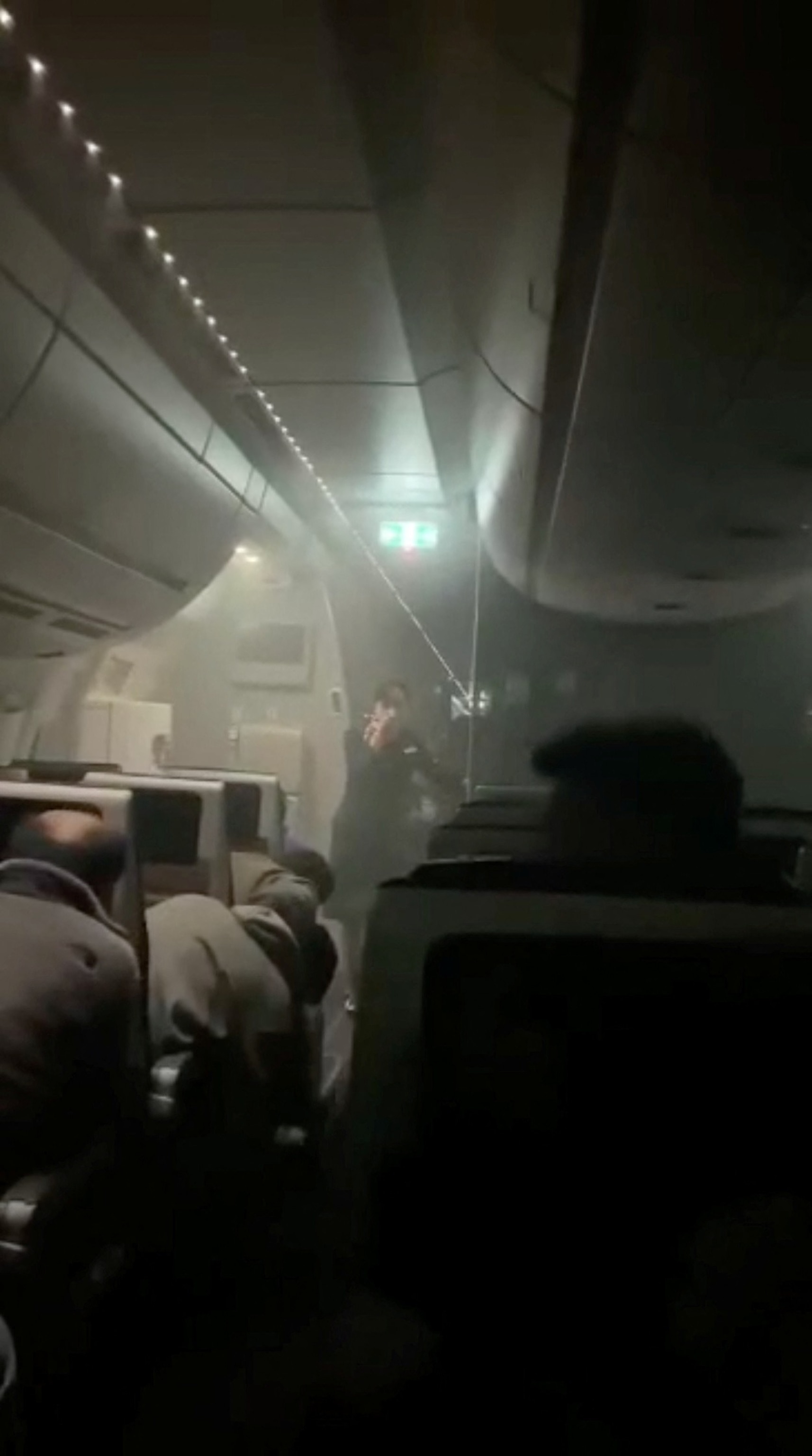 Image: People sit amid smoke inside a Japan Airlines A350 plane in this image obtained from a video on social media.