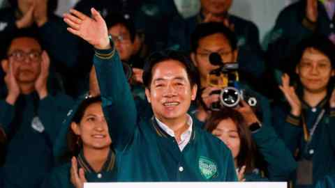 An Asian man waves in front of a crowd of people surrounded by his supporters