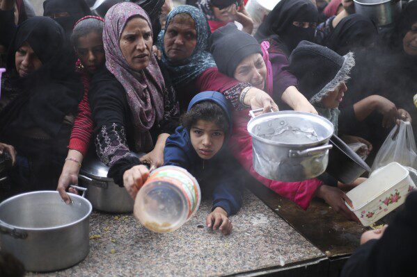 Palestinians line up to distribute free food during the ongoing Israeli air and ground offensive in Khan Yunis, Gaza Strip, Friday, February 2, 2024. (AP Photo/Hatem Ali)