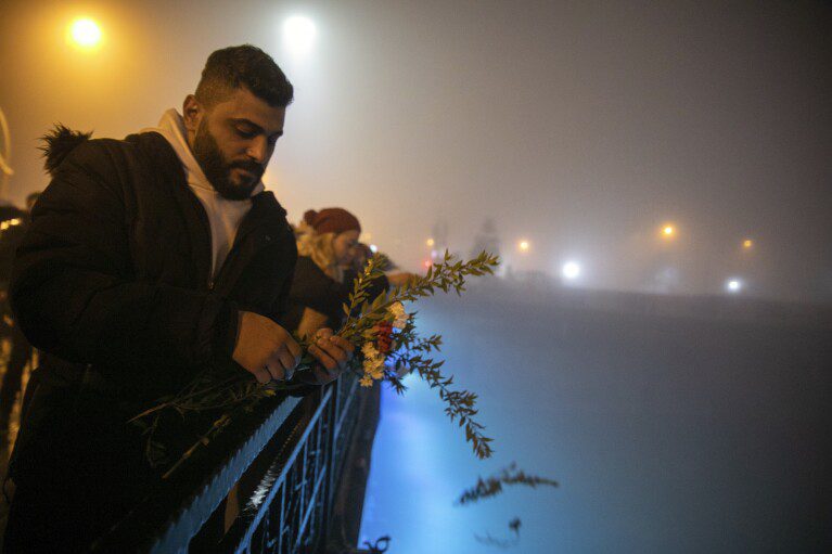 People throw carnations into the Orontes River on the occasion of the first anniversary of the catastrophic earthquake that struck the country, in the city of Antakya, southern Turkey, Tuesday, February 6, 2024. (AP Photo/Metin Yoksu)