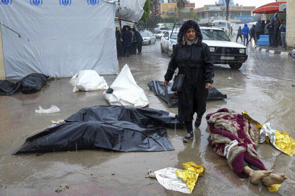 A woman walks among the bodies of Palestinians killed in the Israeli bombing of the Gaza Strip, in front of the morgue of Al-Aqsa Hospital in Deir al-Balah, Gaza Strip, on Sunday, February 18, 2024. (AP Photo/Adel Hana)