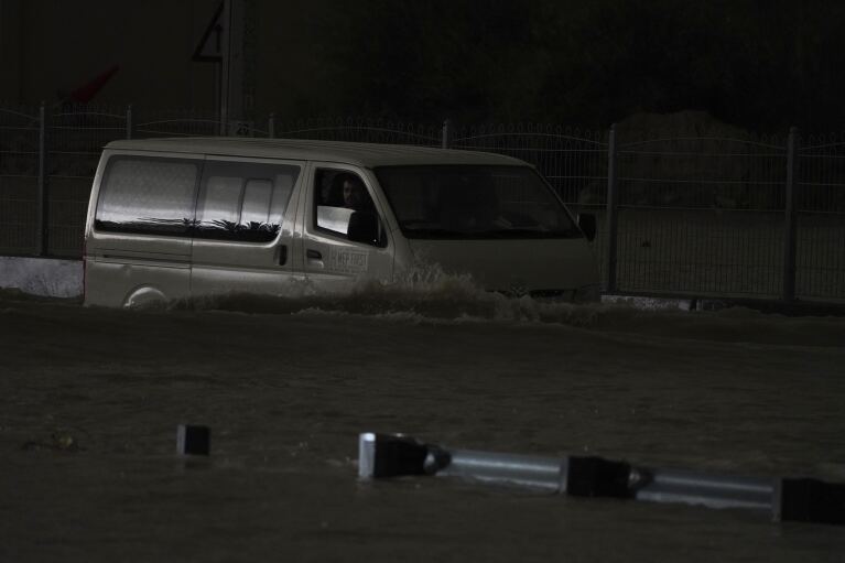 A truck drives through standing water in Dubai, United Arab Emirates, Tuesday, April 16, 2024. Heavy rain hit the United Arab Emirates on Tuesday, submerging parts of major highways and leaving vehicles abandoned on roads across Dubai.  Meanwhile, the death toll in separate heavy floods in neighboring Oman has risen to 18 while others remain missing as the sultanate braces for the storm.  (AP Photo/Jon Gambrell)
